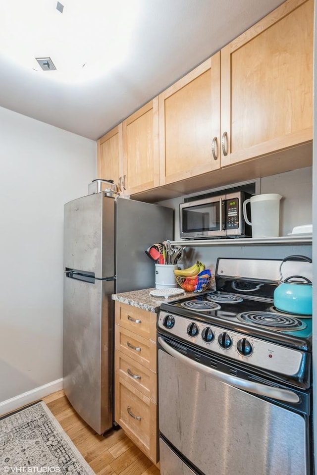 kitchen featuring visible vents, baseboards, light wood-style flooring, appliances with stainless steel finishes, and light brown cabinetry