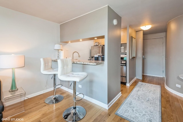 kitchen with light countertops, range, freestanding refrigerator, and light wood-style floors