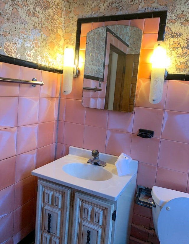 half bathroom featuring wallpapered walls, tile walls, and vanity