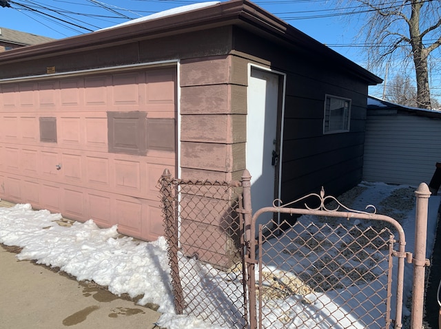 view of side of home featuring a garage, a gate, fence, and an outbuilding