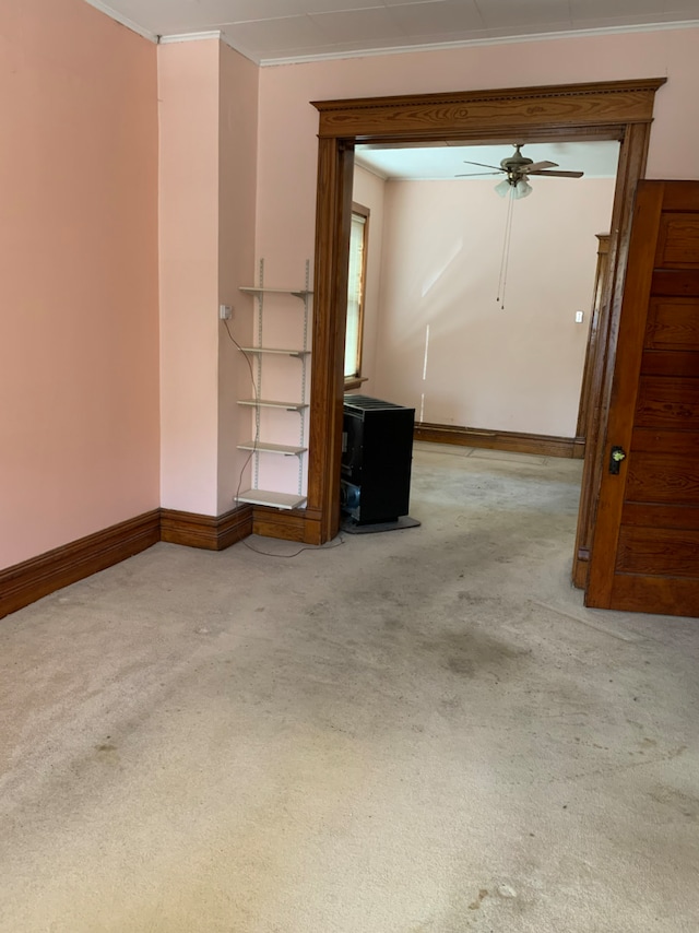 spare room featuring light carpet, ceiling fan, baseboards, and crown molding