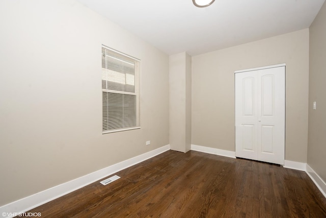 spare room featuring visible vents, dark wood finished floors, and baseboards