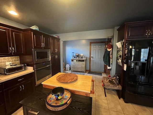 kitchen featuring dark brown cabinetry, a toaster, appliances with stainless steel finishes, backsplash, and light tile patterned flooring