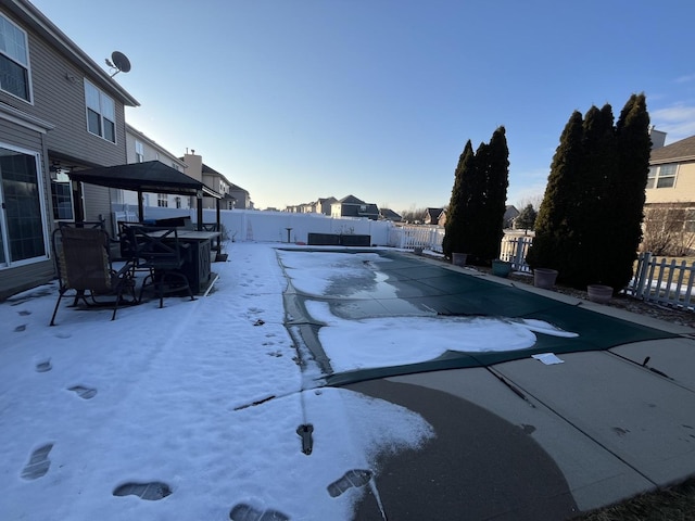 snow covered pool with a fenced backyard and a residential view