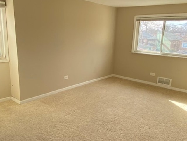 unfurnished room featuring light carpet, visible vents, and baseboards