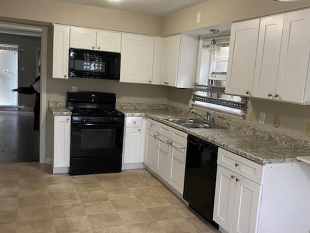 kitchen with light stone countertops, black appliances, white cabinetry, and a sink