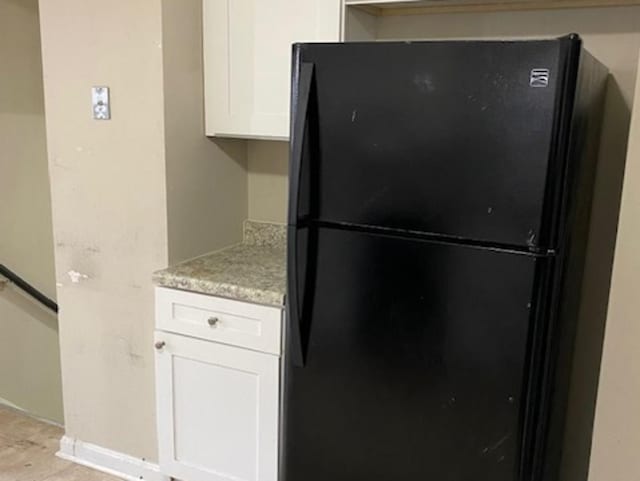 kitchen featuring light countertops, freestanding refrigerator, white cabinets, and baseboards