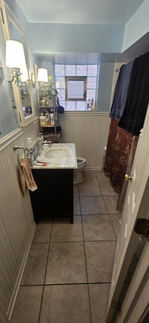 bathroom featuring a wainscoted wall, toilet, vanity, and tile patterned floors