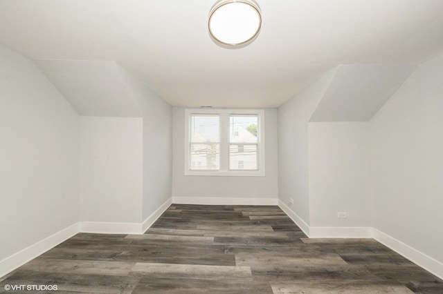 additional living space featuring lofted ceiling, dark wood finished floors, and baseboards