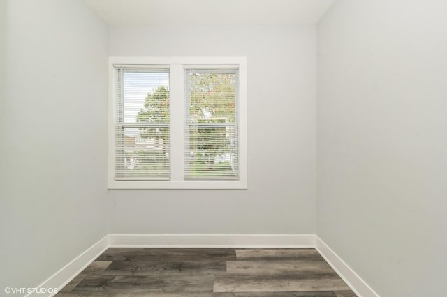 spare room with baseboards and dark wood-type flooring