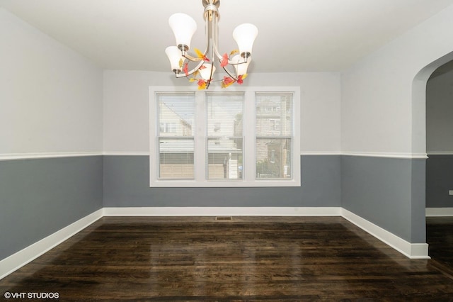 unfurnished dining area featuring arched walkways, dark wood-style flooring, visible vents, baseboards, and an inviting chandelier