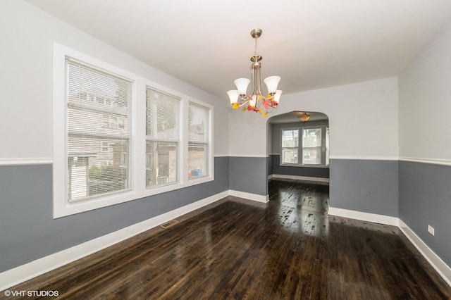 unfurnished dining area featuring dark wood-style floors, arched walkways, visible vents, and baseboards