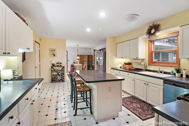 kitchen featuring stainless steel appliances, dark countertops, white cabinets, and a sink