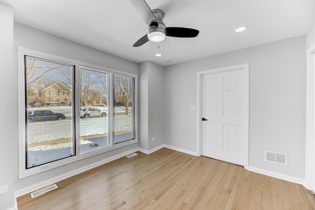 empty room featuring light wood-style floors, recessed lighting, visible vents, and baseboards