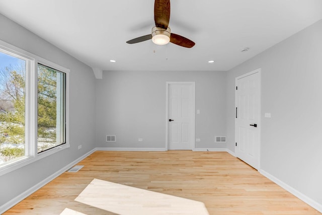 empty room with light wood finished floors, baseboards, and visible vents