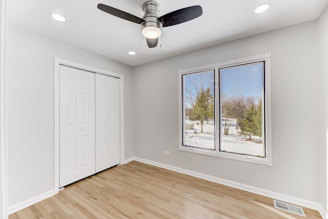 unfurnished bedroom featuring recessed lighting, a closet, visible vents, light wood-type flooring, and baseboards