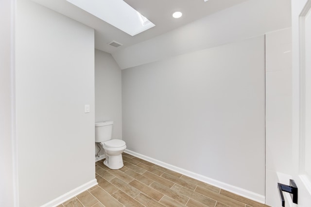 bathroom with visible vents, toilet, wood tiled floor, vaulted ceiling with skylight, and baseboards