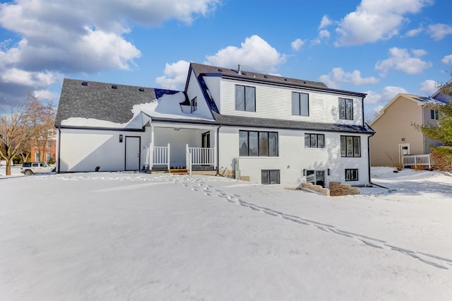 snow covered rear of property with a porch