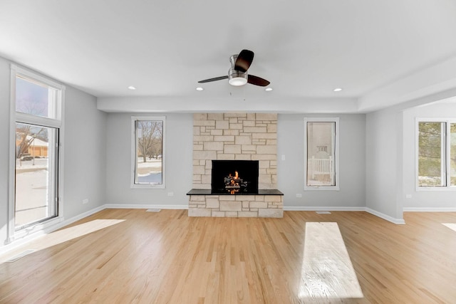 unfurnished living room with light wood-style floors, recessed lighting, a stone fireplace, and baseboards