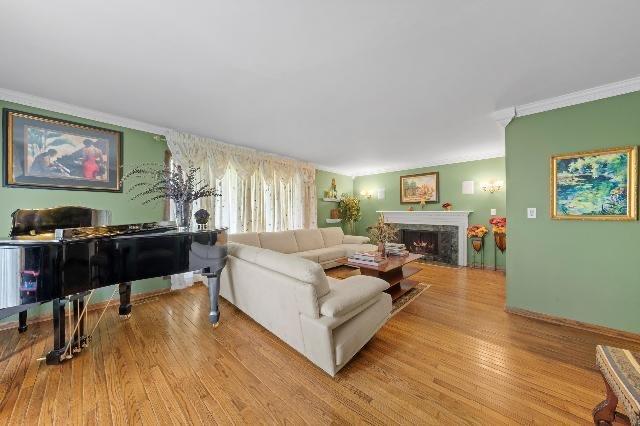 living area featuring light wood-style flooring, crown molding, and a high end fireplace