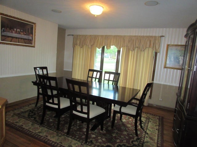 dining room with wainscoting, wood finished floors, and wallpapered walls