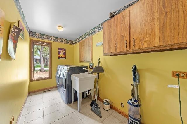 washroom with separate washer and dryer, light tile patterned flooring, cabinet space, and baseboards