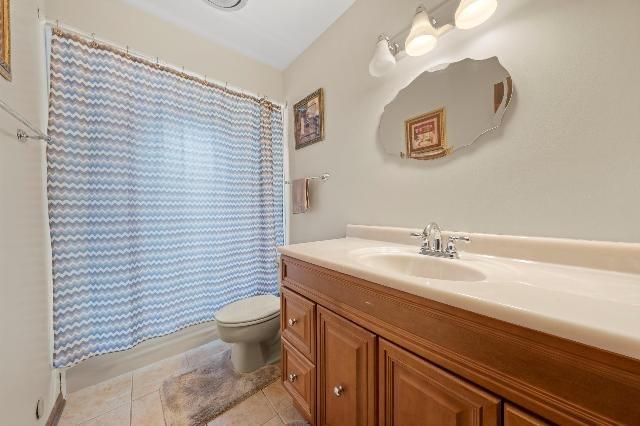 bathroom featuring toilet, a shower with curtain, vanity, and tile patterned floors