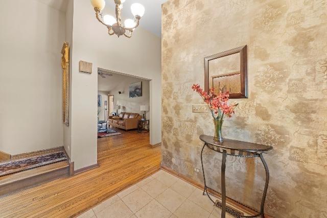 foyer entrance featuring light tile patterned floors, a high ceiling, baseboards, and a notable chandelier