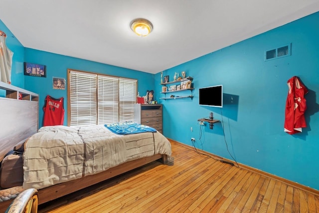 bedroom with wood-type flooring, visible vents, and baseboards