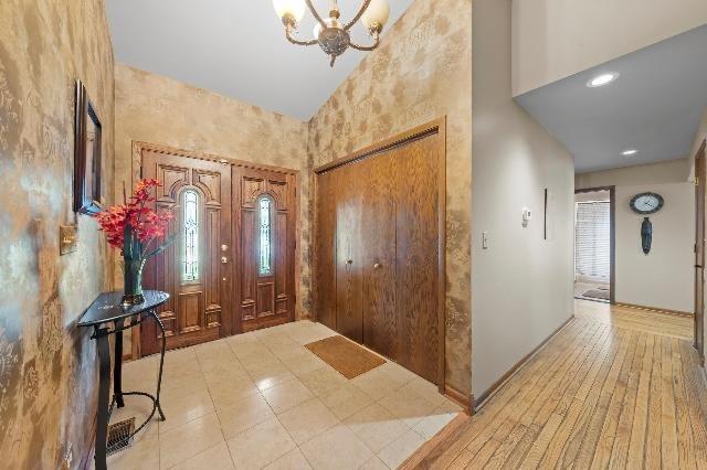 foyer with high vaulted ceiling, a notable chandelier, and hardwood / wood-style floors