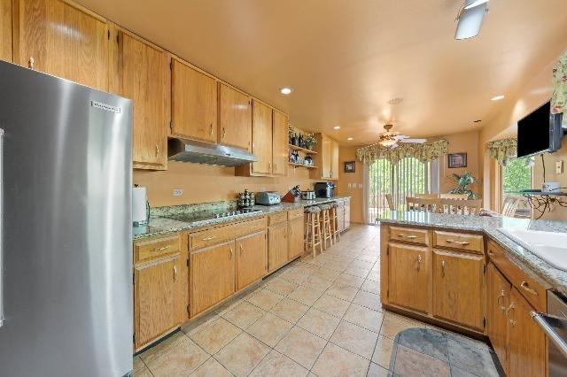 kitchen featuring ceiling fan, stainless steel appliances, light countertops, under cabinet range hood, and light tile patterned flooring