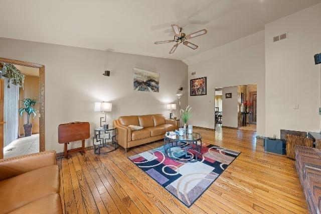 living area with vaulted ceiling, ceiling fan, hardwood / wood-style floors, and visible vents