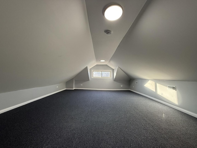 additional living space with carpet floors, visible vents, baseboards, and vaulted ceiling