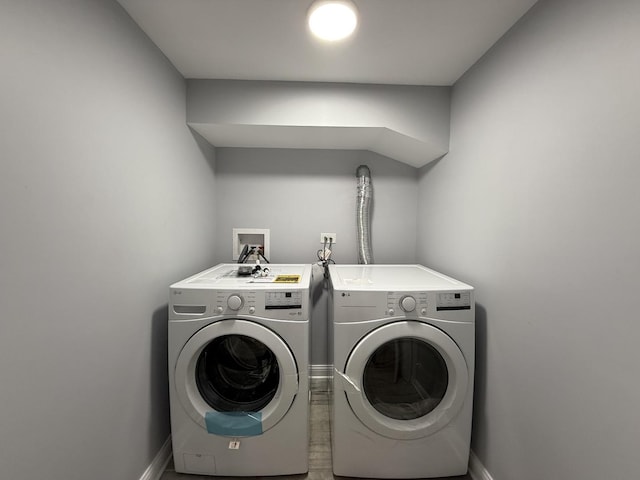 washroom with laundry area, washing machine and dryer, and baseboards