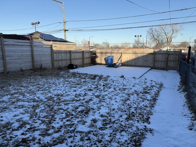 yard layered in snow featuring a fenced backyard