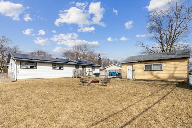 rear view of house featuring an outdoor fire pit, a lawn, and fence