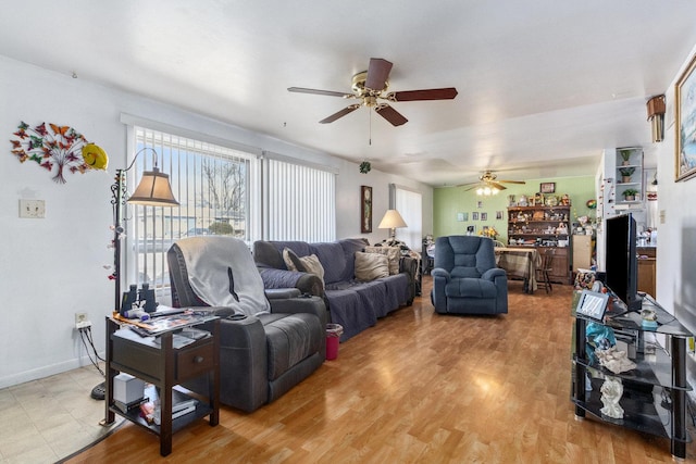 living area with baseboards, ceiling fan, and light wood finished floors