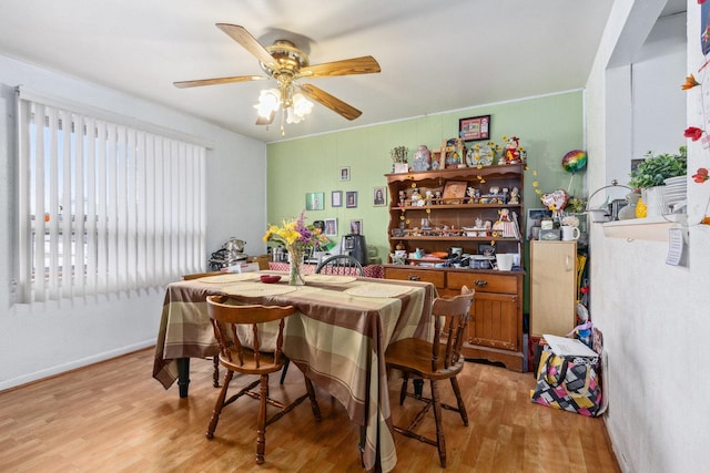 dining area featuring a ceiling fan, baseboards, and light wood finished floors