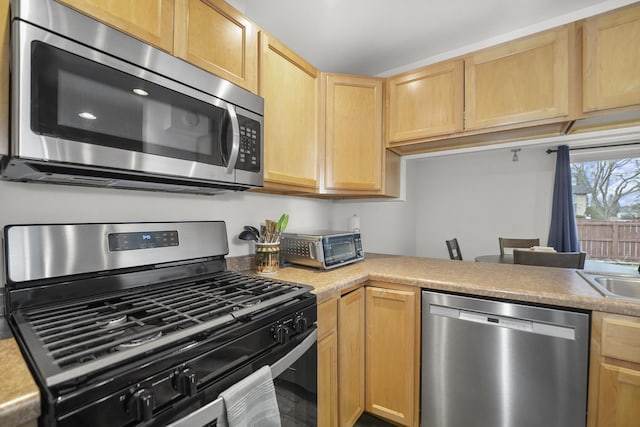 kitchen featuring light brown cabinets, stainless steel appliances, and light countertops