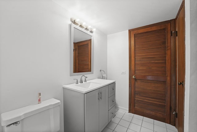 bathroom with a closet, tile patterned flooring, vanity, and toilet