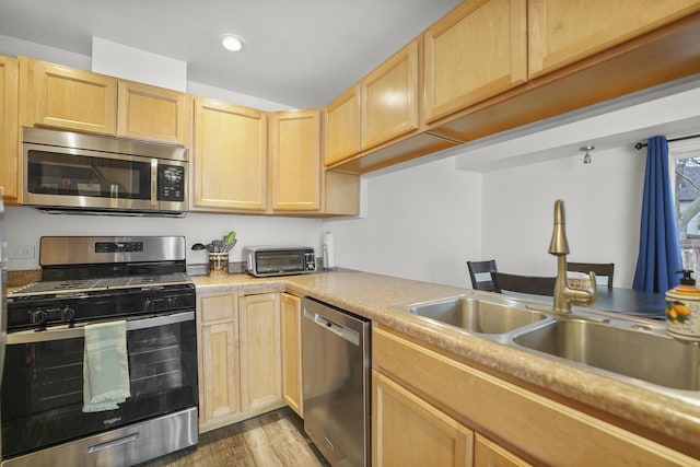 kitchen featuring stainless steel appliances, light countertops, and light brown cabinetry