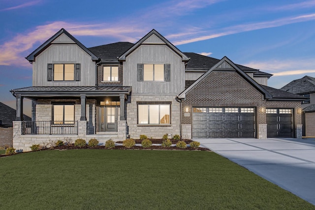 modern farmhouse style home featuring metal roof, an attached garage, concrete driveway, a lawn, and a standing seam roof