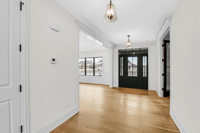 foyer with crown molding, light wood finished floors, and baseboards