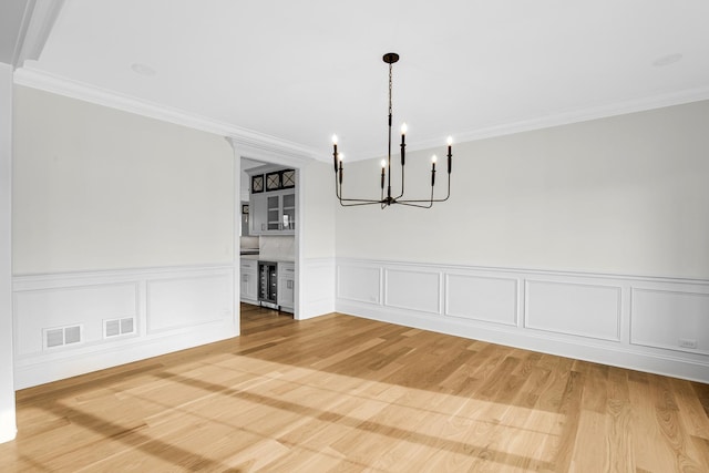 unfurnished dining area with light wood-type flooring, beverage cooler, visible vents, and crown molding