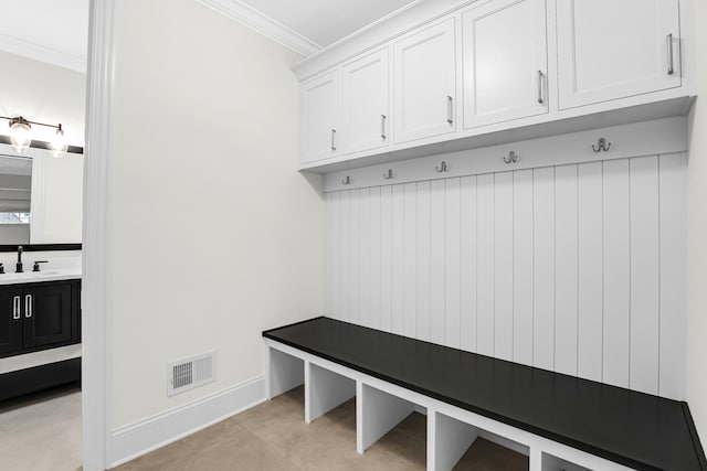 mudroom with ornamental molding, visible vents, a sink, and baseboards