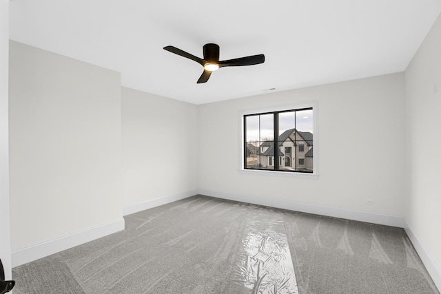 empty room with carpet flooring, a ceiling fan, and baseboards