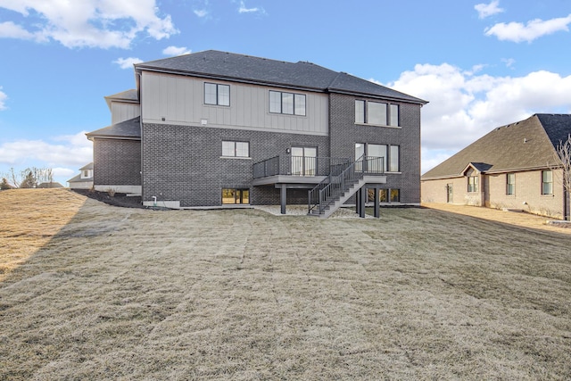 rear view of property featuring brick siding, a lawn, a deck, and stairs