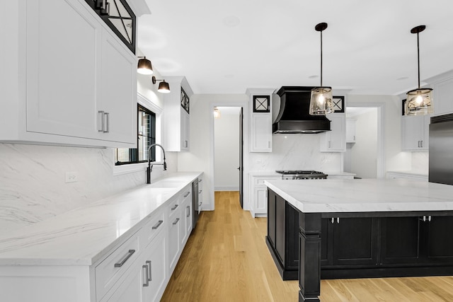 kitchen featuring a sink, custom exhaust hood, dark cabinetry, light wood-style floors, and stainless steel dishwasher