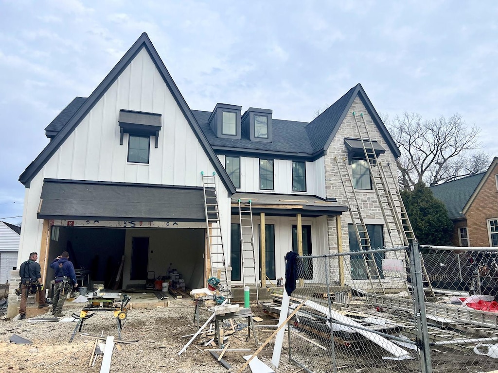 view of front of home with a garage, board and batten siding, covered porch, and fence