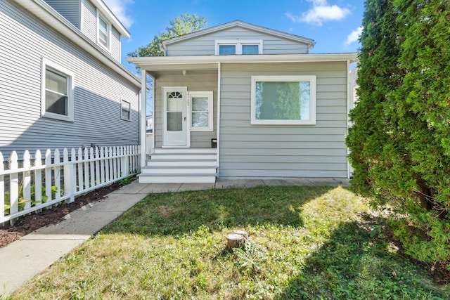 view of front of property with entry steps, a front lawn, and fence